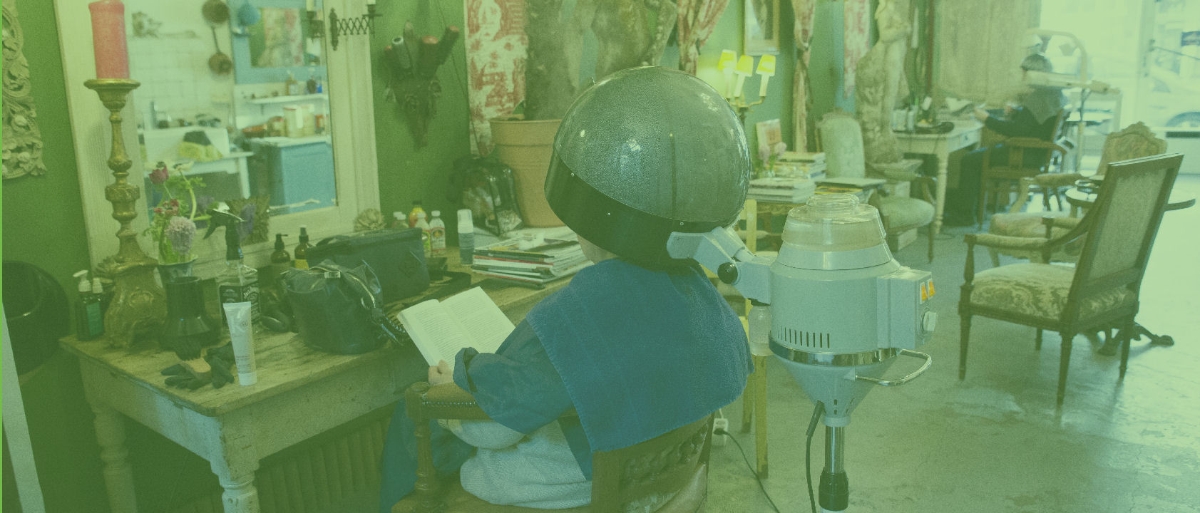 Klant onder de stoomkap in Huis van Groen, lezend in een boek